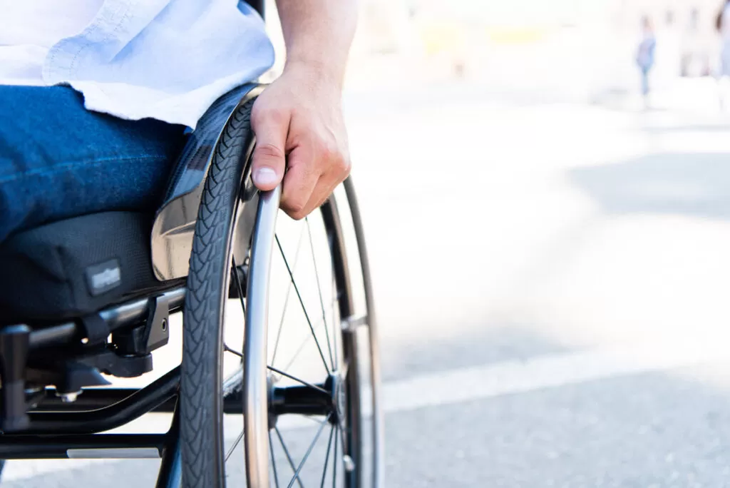 A close-up of a person’s hand on a wheelchair wheel in El Paso.